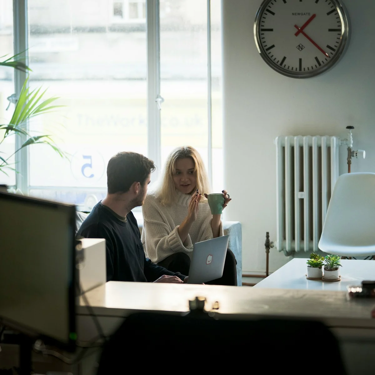 Two colleagues collaborating near an office window